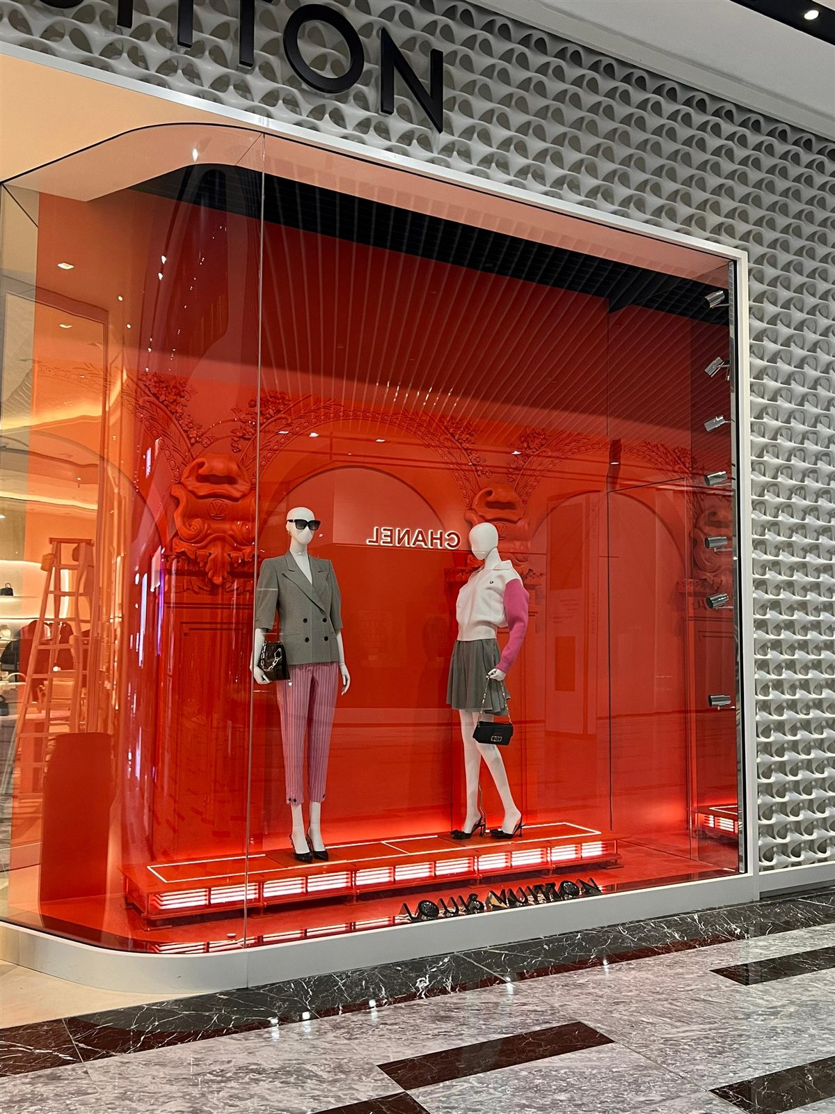 Campaign window with sculpted red archway at a luxury maison flagship